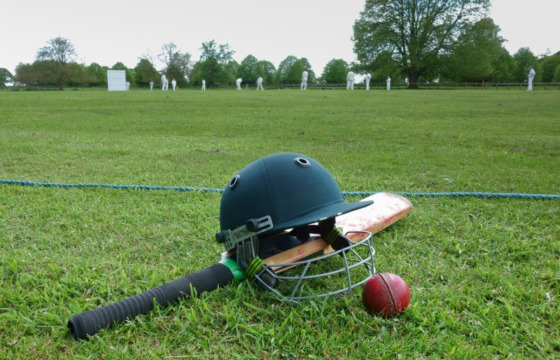 Cricket, bat, ball and cricket helmet on edge of greenpitch Stock Image