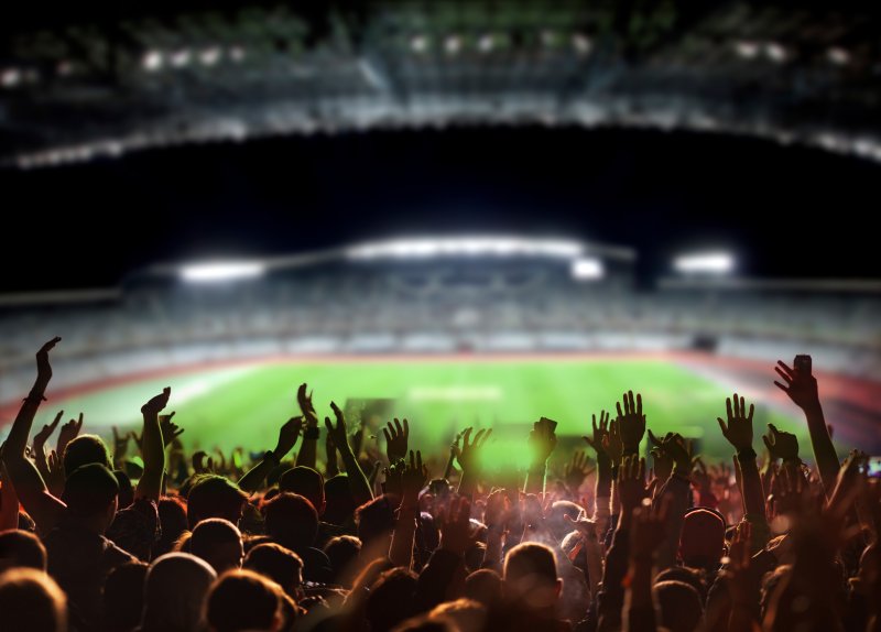 Football supporters cheering at a stadium, arty shot from behind Stock Image